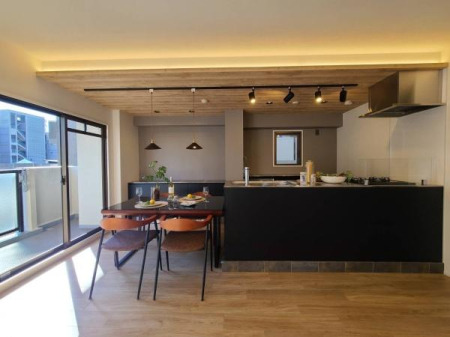 キッチン　黒の面材とステンレス素材のキッチン。天井は木目調で設え優雅な空間を演出。